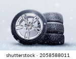 Small photo of winter studded tires, a set of friction winter wheels with aluminum alloy wheels on a white background. falling snow is a safety concept about seasonal tire change for safety on the road in icy