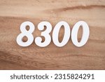 Small photo of White number 8300 on a brown and light brown wooden background.