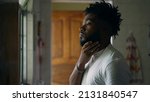 Small photo of A worried black man standing by window in preoccupation