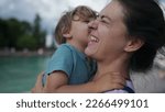 Small photo of Funny mother and son moment. Little boy kissing mom in cheek pretending to be disgusted. Family lifestyle bonding moment. Authentic real life