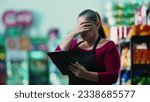 Small photo of Stressed female entrepreneur owner of small business struggling with hard times holding tablet and staring at the bottom line of the grocery store