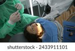 Small photo of Apprehensive little girl seated at Dentist office before teeth procedure. Doctor getting ready while 8 year old child observes with anxious preoccupation, overhead view