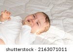 Small photo of cute little baby boy is crying. toddler on bed, white blanket,sunny rays, morning situation.motherhood. teething period,bloating belly pain, want to sleep,eat, hungry child