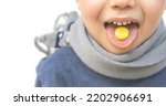Small photo of kid hold on tongue anaesthetic sore throat lozenges for pain redness irritation treatment.isolated on white child with scarf around neck.sweet candy yellow color lemon honey ingredients.wide banner