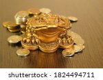 A metal toad next to a stack of coins. Symbol of happiness and financial success.
