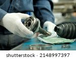 Small photo of Car maintenance and repair in the car center. A joint of equal angular velocities in the hands of an auto mechanic. Inspection and control of the conformity and integrity of the spare part.