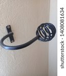 Small photo of A curtain holdback mounted beside a window. A hold back used to keep the curtain open. Coiled design of a curtain hold back.