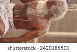 Small photo of Varanasi, Uttar Pradesh, India-Jan 18 2023: Close up portrait of an holy sadhu baba performing the rituals pooja at manikarnika ghat in kashi. White beard baba portrait unedited at the ghats, Banaras