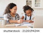 Small photo of Tutoring homeschooling concept. African mother mom nanny childminder helping daughter with homework, drawing together, e-learning, preparing for school art project at home.