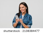 Small photo of Smiling caucasian young woman listening to the podcast e-book music song singer rock band in earphones, choosing sound track on cellphone isolated in white background