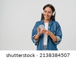 Smiling caucasian young woman listening to the podcast e-book music song singer rock band in headphones earphones, choosing sound track on cellphone isolated in white background