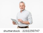 Small photo of Smart caucasian mature middle-aged senior freelancer grandfather ceo boss teacher professor using digital tablet for remote work online, watching webinars isolated in white background