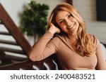 Small photo of Close up photo of beautiful middle aged woman relaxing on sofa at home. Portrait of mature caucasian woman looking at camera. Unaltered beauty