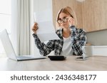 Small photo of Stressed young female paying domestic bills, having problems with billing overdue at home kitchen. Confused woman received report debt loan papers