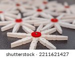 Wooden clothespin in the form of a snowflake with a red button,  close-up. Preparation of DIY crafts, handmade and creative, inspiration.