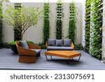 Small photo of two stylish wooden chairs with cushions and a small wooden table at a balcony of a room in a resort, surrounded by garden