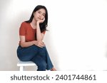 Bored looking Asian woman sitting alone on high stool waiting for someone