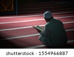 Small photo of An unknown person is reading the Koran with solemnity in a mosque. Medan, Indonesia - June 12,2016.