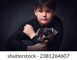 Little boy with a dog on a dark background. Studio shot.
