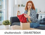 Small photo of Embittered woman opening just delivered item after home shopping