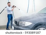Man washing his car in a self-service car wash station