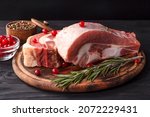 Small photo of Several pieces of fresh raw beef brisket on the bone with cranberries and rosemary on a wooden board