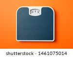 Small photo of Blue weigh scales on orange background, top view