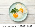 Plate with fried eggs on wooden background, top view