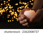 Mourning candles in hands, on a dark background.