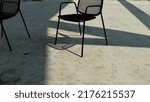 Small photo of An empty chair is placed on the floor of the unadorned cement. The shadow created by the afternoon sun creates a rather abstract image.