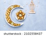 Small photo of Traditional middle eastern dessert baklava in shape of moon and star . Ramadan background with sweets and lantern , Top view, flat lay , copy space