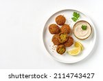 Small photo of Plate of chickpeas falafel with tahini sauce isolated on white background. Top view, copy space