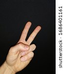 Small photo of Left hand “Peace” gesture (underhand). isolated black background, male hand