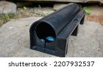 Small photo of A black plastic rat trap on concrete floor. bait poison box for rat. A black plastic rat trap (baiting box). Pest control concept image.