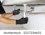 Small photo of Technician plumber using a wrench to repair a water pipe under the sink. Concept of maintenance, fix water plumbing leaks, replace the kitchen sink drain, cleaning clogged pipes is dirty or rusty.