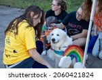 Small photo of Athens, Georgia - October 10, 2021: Two dogs in costume rest in the shade with volunteers during the Boo-Le-Bark costume contest at the Jittery Joe's Roaster, a fundraising event for AthensPets.