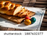 Small photo of Easter breakfast, Striezel, yeast wreath, plait on a bread board, with colored eggs. plaited or braided, yeast bun