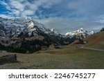 Panorama with new wooden hotels and old destroyed hut in shadow valley with illuminated snowy mountains in background. on the road again through Bregenz forest and Austrians mountains. impressive mood