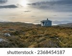 gray painted hut on Norwegian mountain, with view of fjord and coastal landscape of Norway. Ski lodge near Tromsø in colorful autumn. rough rocky landscape with colorful plants.