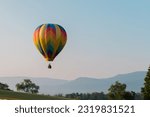 Small photo of A brightly colored hot air balloon over a mountainous landscape in Wytheville Virginia during the Chautauqua Balloon Festival.