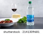 Small photo of Los Angeles, California, United States - 03-01-2022: A view of a bottle of Dasani, with an entree of of meatballs in marinara sauce.