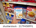 Small photo of Los Angeles, California, United States - 05-20-2022: A view of a hand holding a package of Jiffy blueberry muffin mix, on display at a local grocery store.