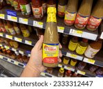 Small photo of Los Angeles, California, United States - 05-05-2023: A view of a hand holding a bottle of Mang Tomas all purpose sauce, on display at a local grocery store.
