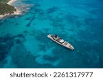 Small photo of An impressive open yacht near the shore, created specifically for communication and relaxation, view from above. Anchorage of a large yacht on transparent water, top view.