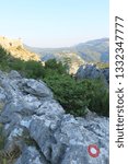 Small photo of A marked difficult mountain trail with large stones among green trees to Mirabela Fortress in Omis Croatia on a summer day. Concept trekking and hiking trips