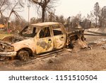 Charred truck in front of home burned to the ground in the recent wild fire fire storm in Redding, California. Smoke and ash in the air as the fire continues to burn several miles away.