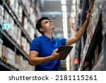 Warehouse Worker using digital tablets to check the stock inventory in large warehouses, a Smart warehouse management system, supply chain and logistic network technology concept.