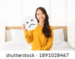 Asian beautiful woman happy and smile sitting on bed with holding paper sad emoticon symbol