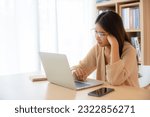 Small photo of Young Asian Woman Working on Computer Laptop in the Living Room, Experiencing Emotional Turmoil, Serious, Stress, Loneliness, Anxiety, and Despair