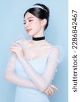 Small photo of Princess concept. Asian woman with korean makeup on face have plump lips and clean fresh skin on isolated blue background. Portrait of cute female model in studio. Facial treatment, Cosmetology.